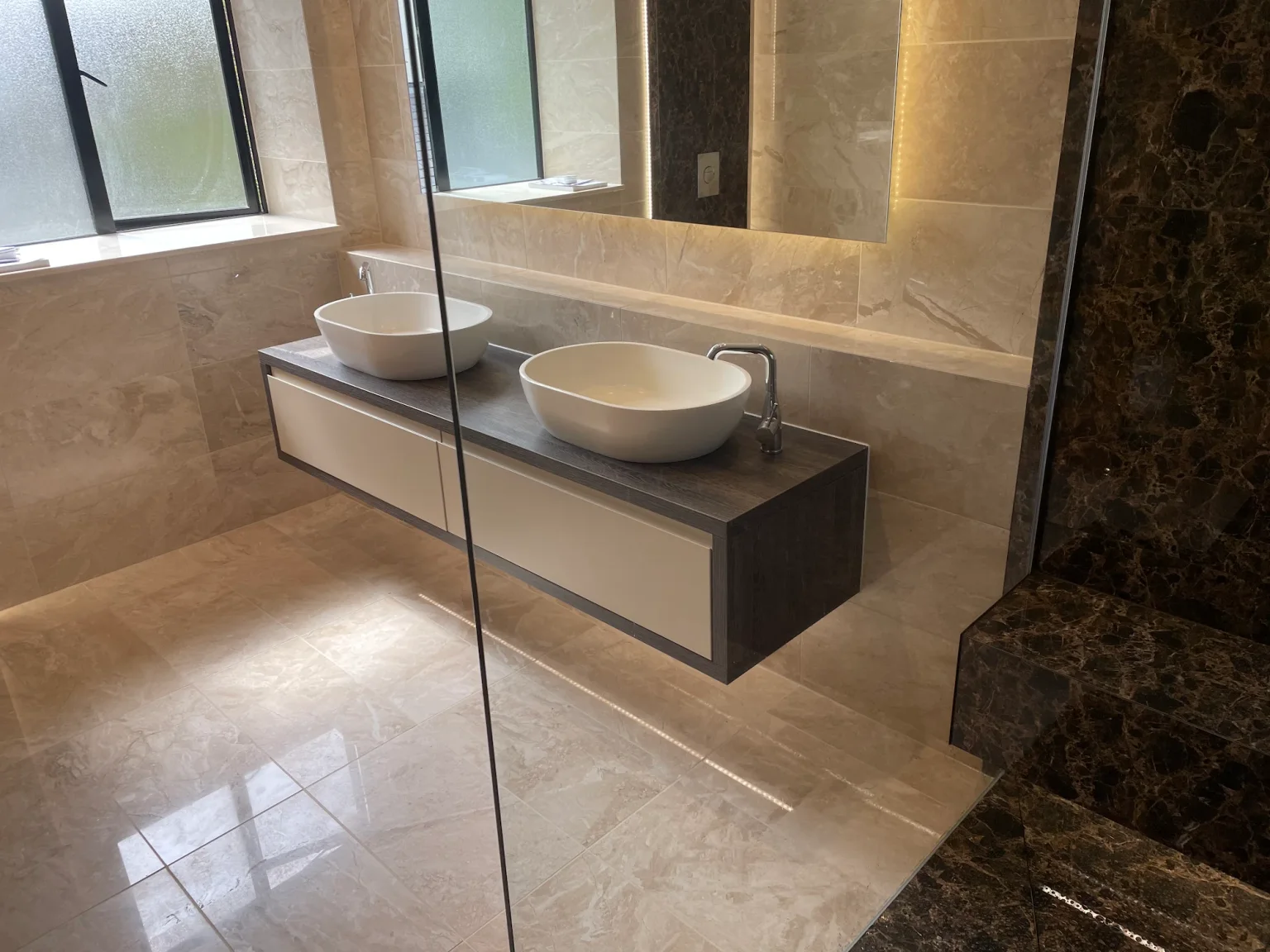 Completed client bathroom with a floating double vanity and contrasting stone finishes