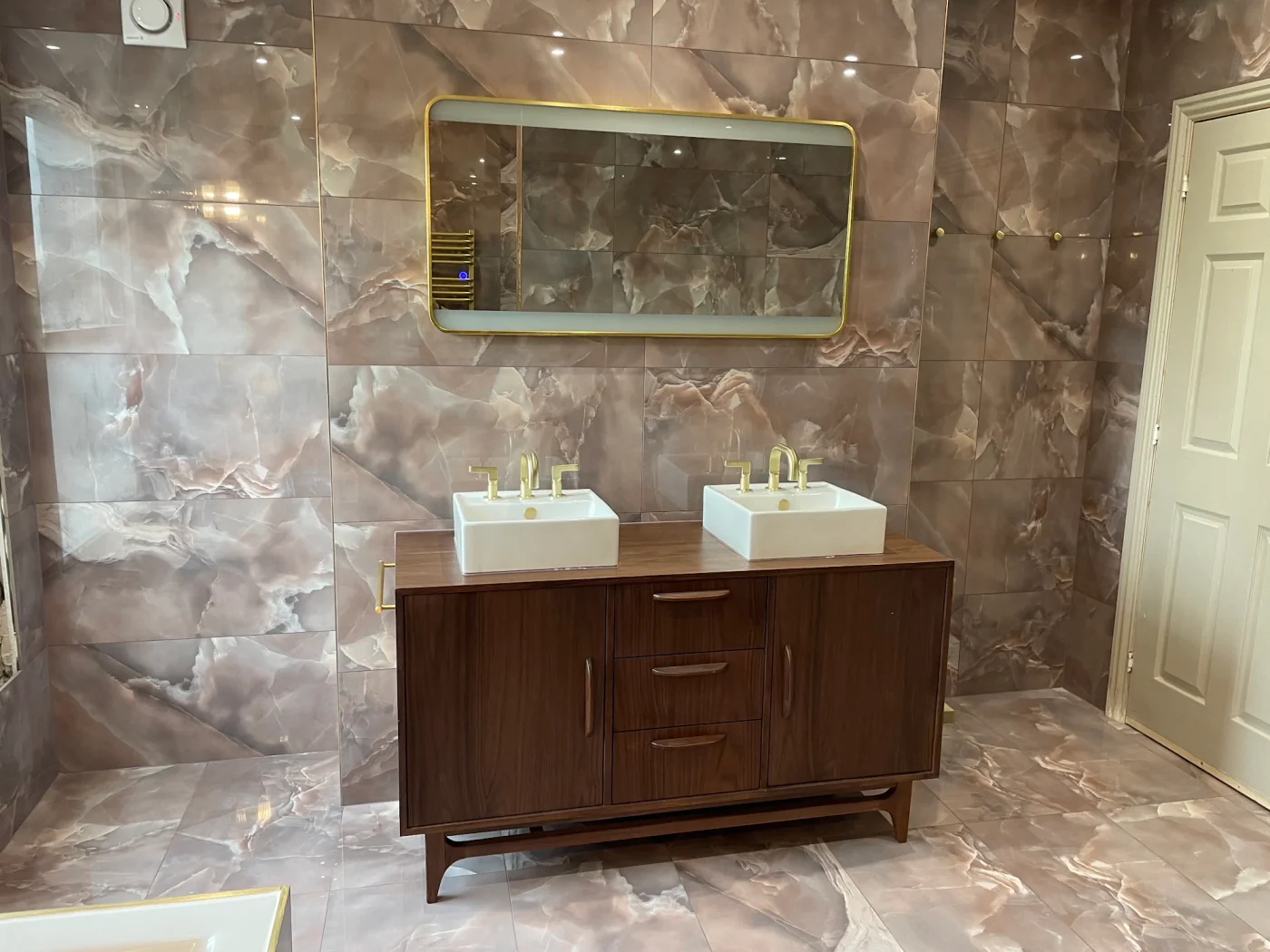 Twin basins and brass taps against expressive marble-effect tiles