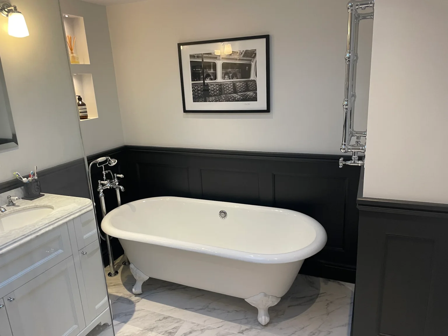 White roll-top bath, traditional vanity and dark wall panelling